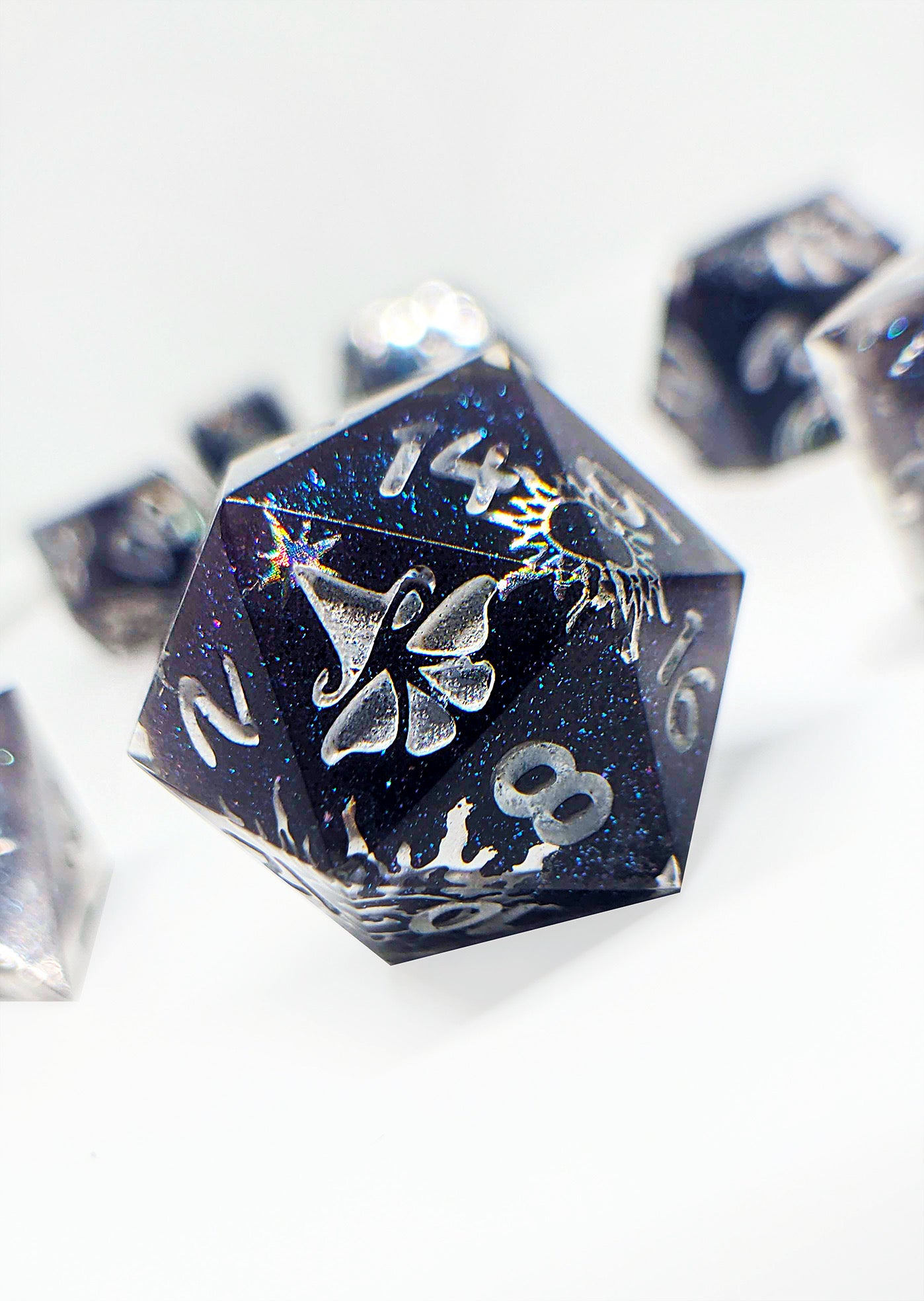 D20 polyhedral die with a silver moth design on the 20 side