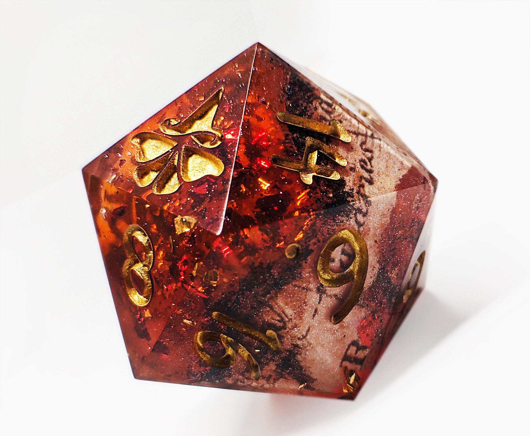 A red, sparkling polyhedral d20 die with gold numbering on a white background.