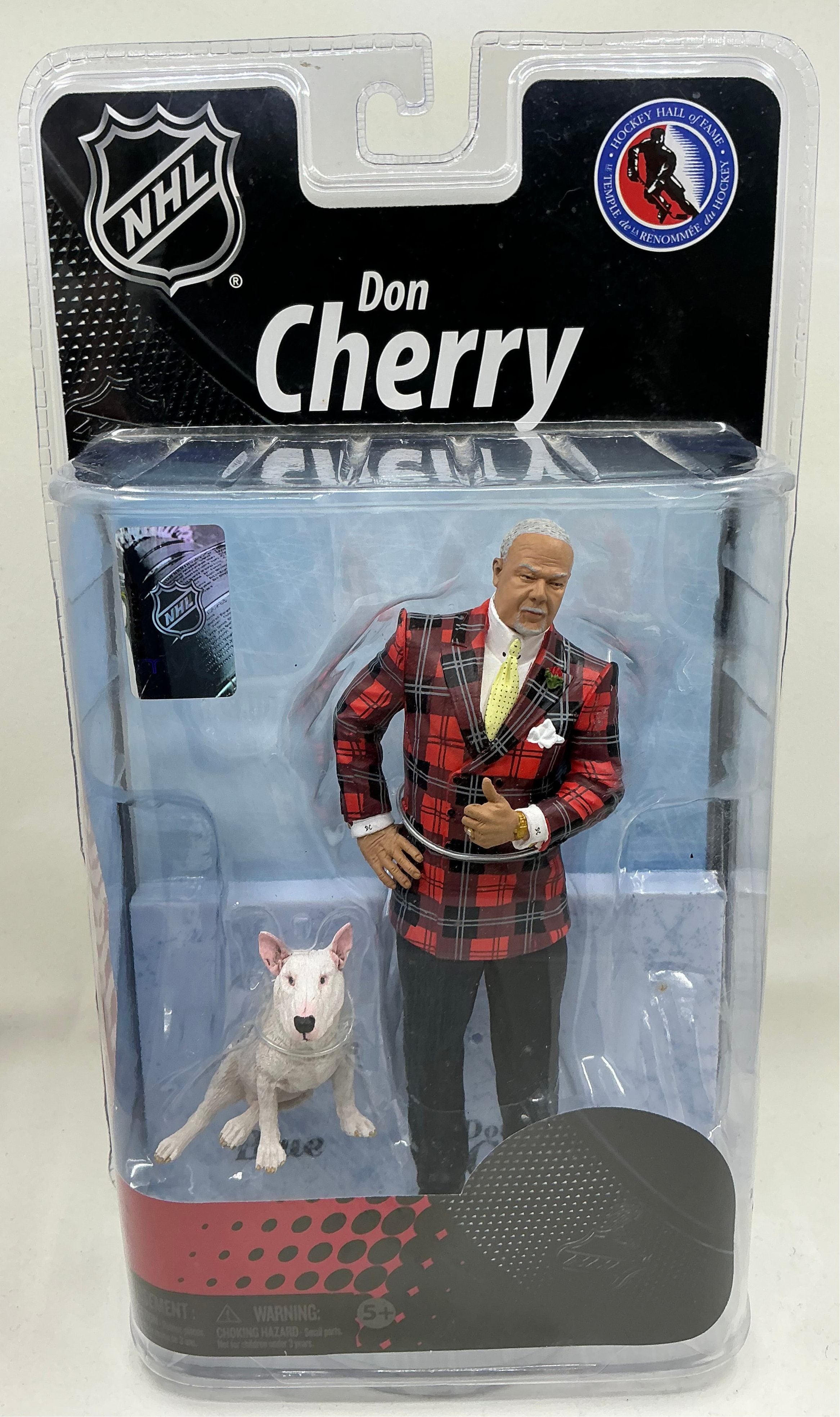 Action figure of Don Cherry in a red plaid suit with a dog, packaging featuring NHL logo.