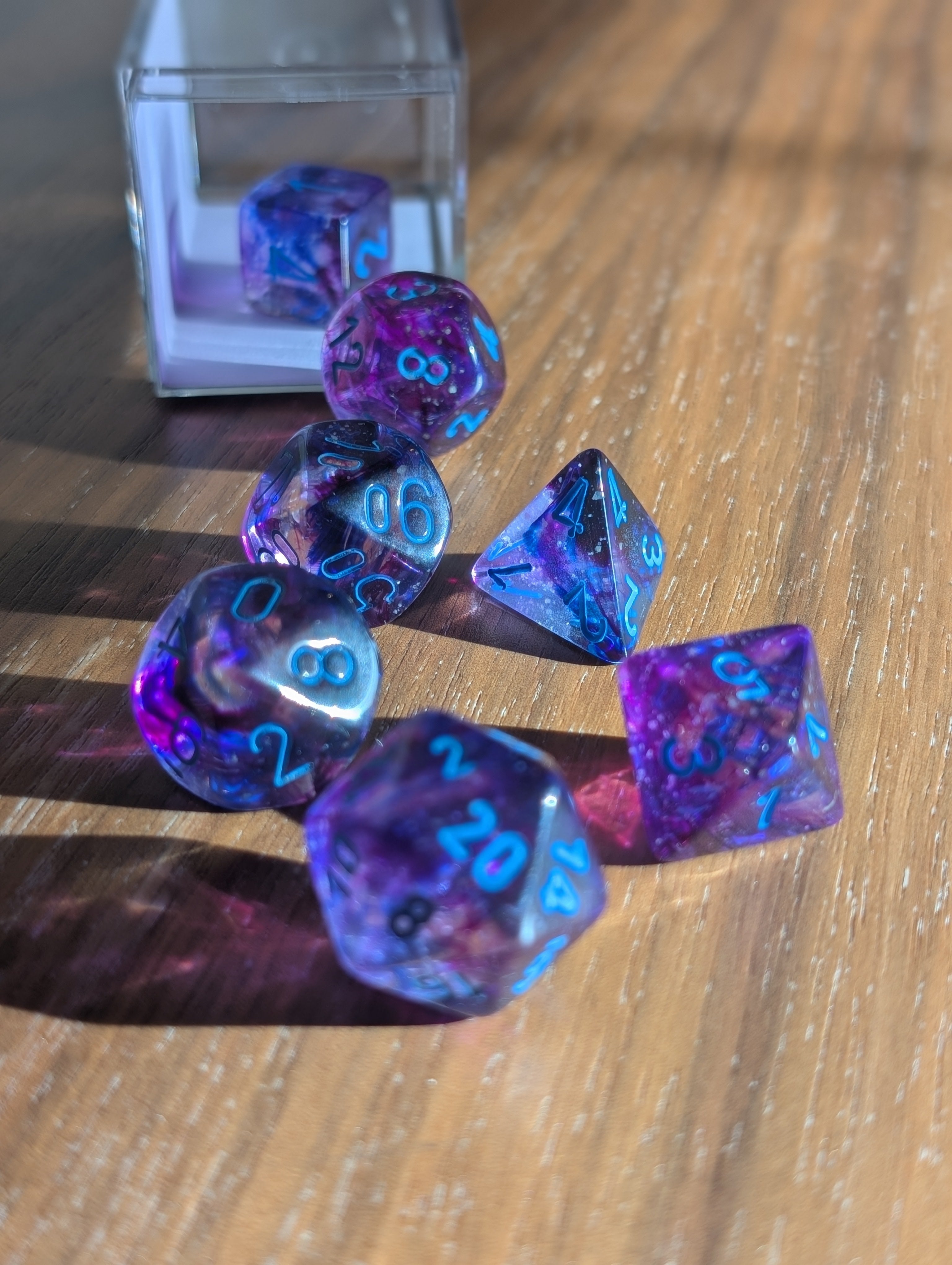 A set of translucent purple polyhedral dice spills out of a clear container toward the camera.